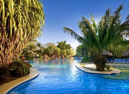 Luxury resort pool surrounded by palm trees in Costa Rica vacation package